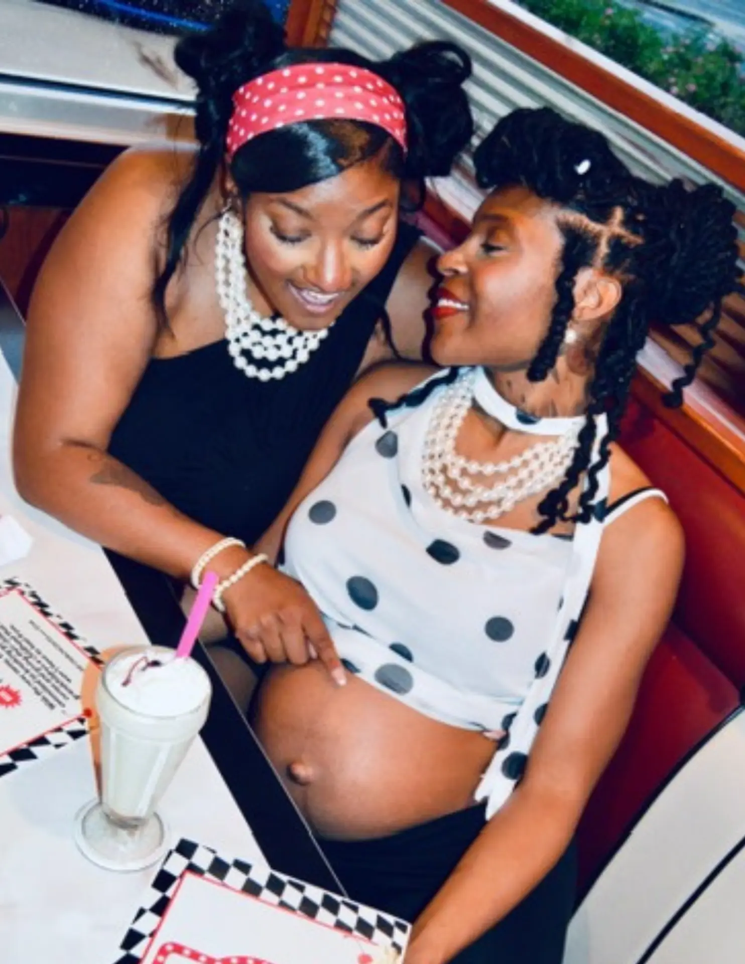 Two women sharing a joyful maternity moment together at a diner
