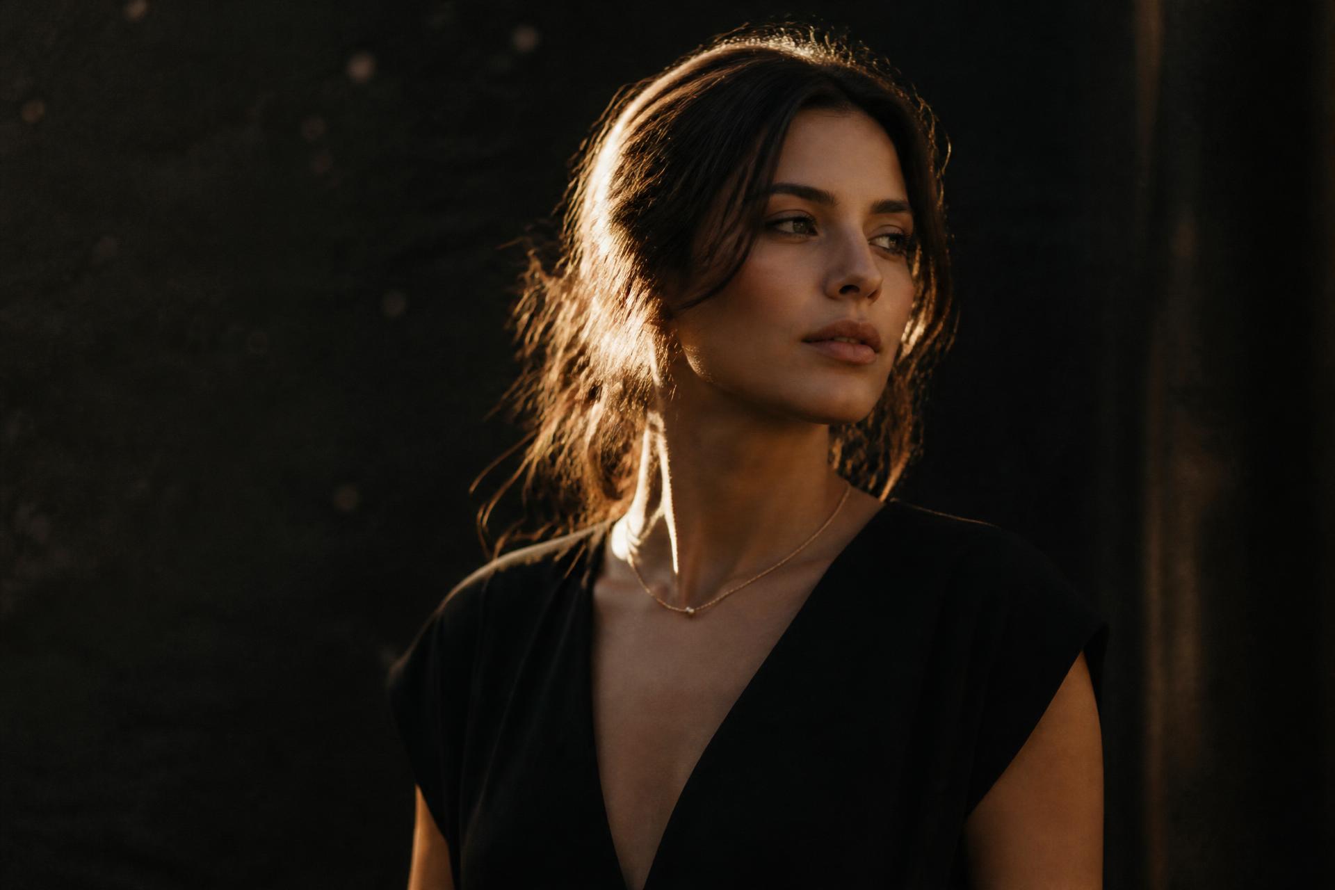 Portrait session at golden hour: a woman lit by warm low sunlight against deep shadow